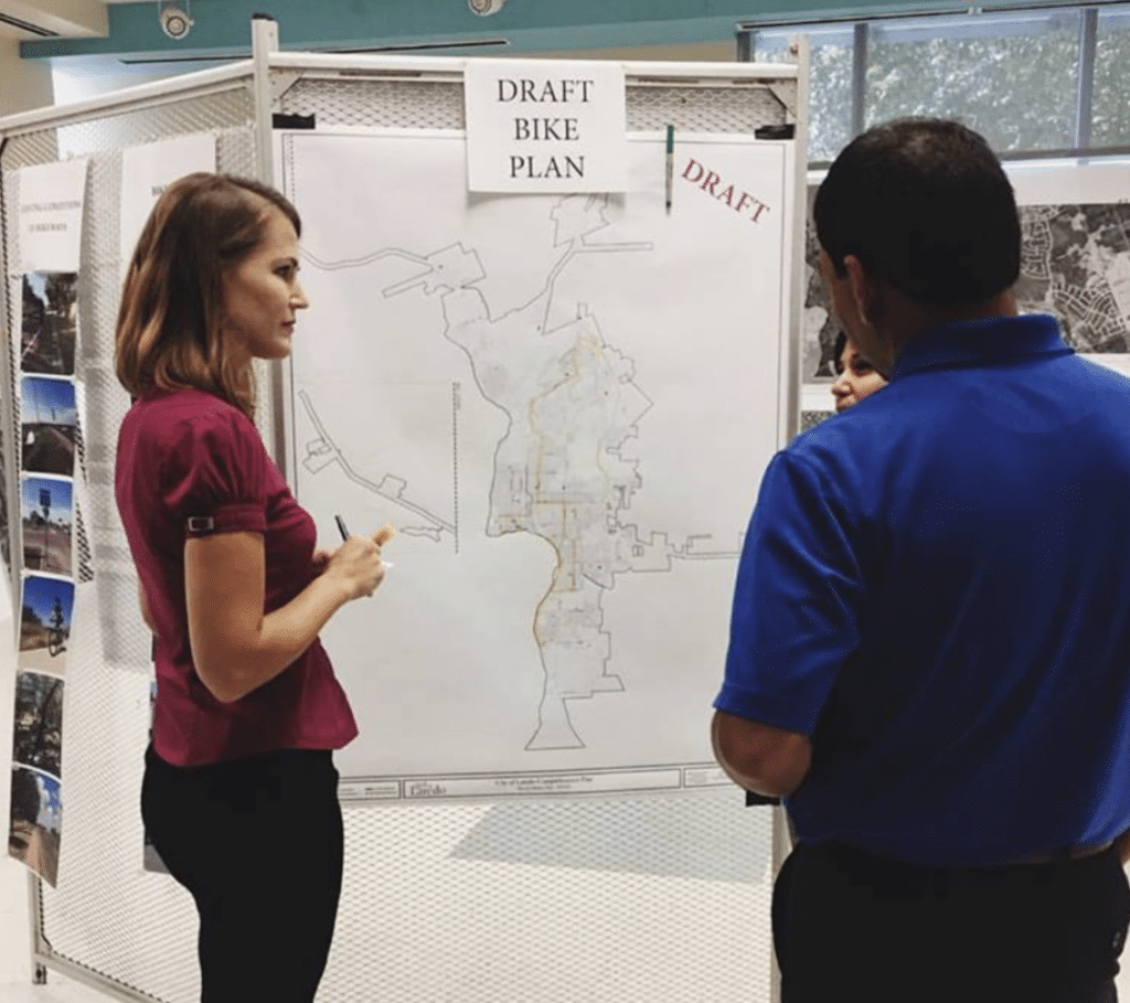 Woman in front of map with man to her right